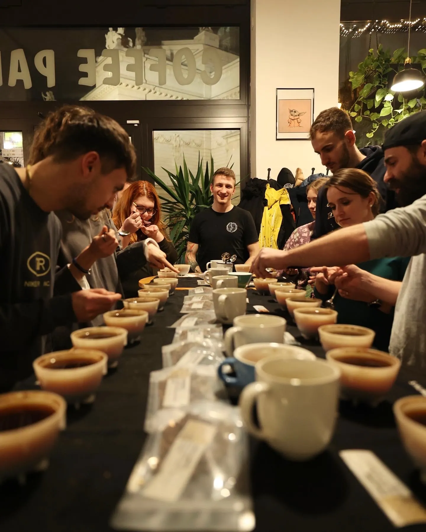Cupping v kavárně, hosté ochutnávají kávu u dlouhého stolu