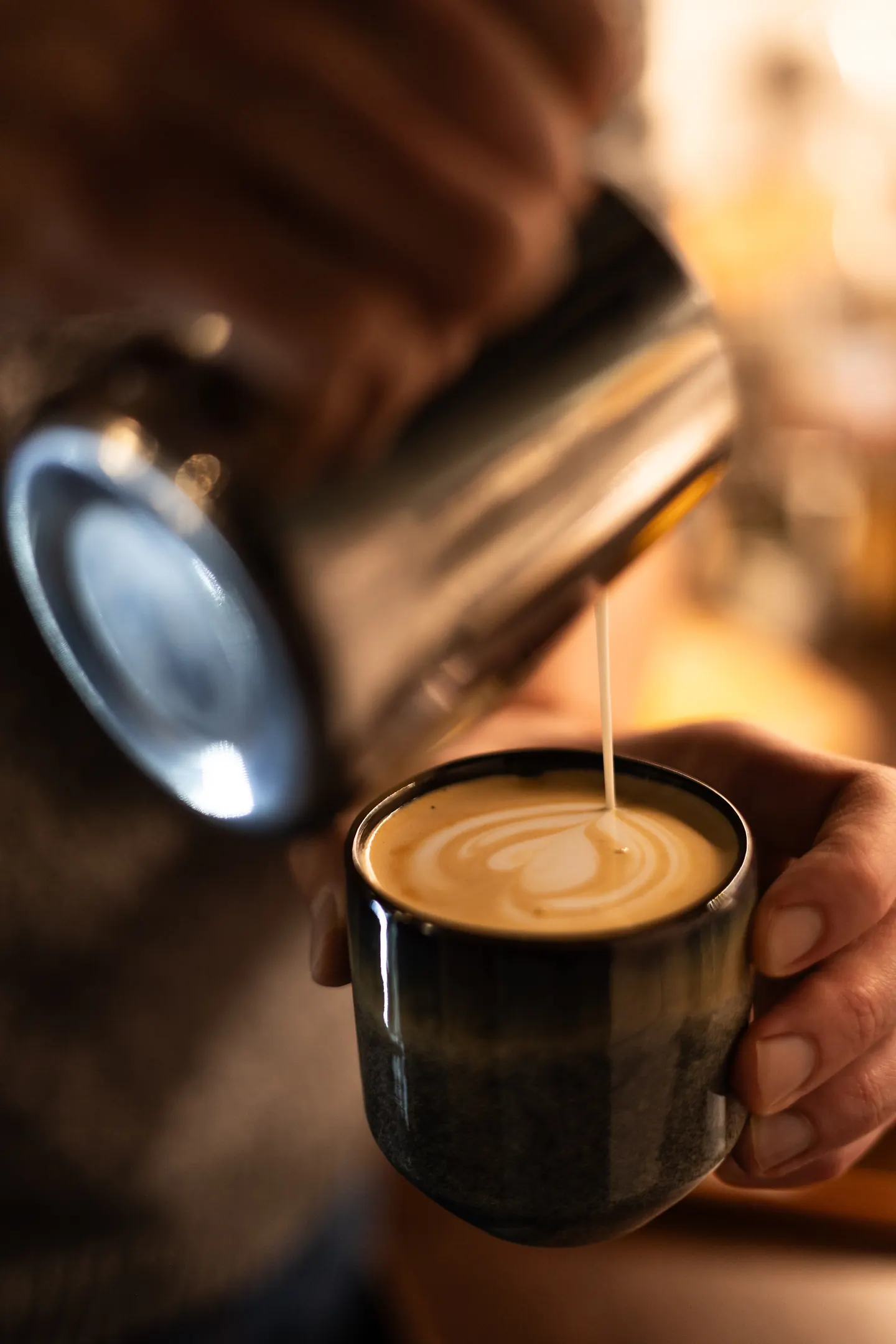 Barista dolévá mléko do šálku kávy