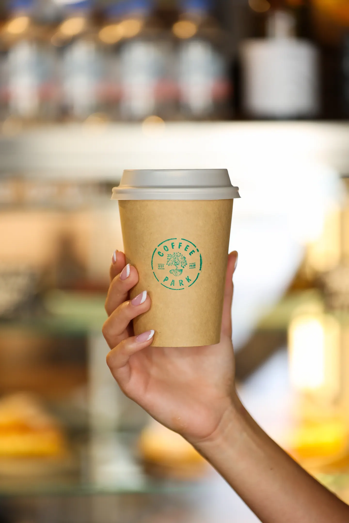 Ruka drží papírový kelímek s logem Coffee Park